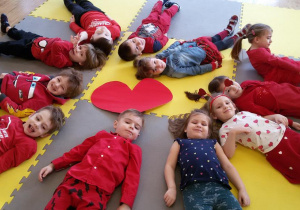 Widok na dzieci leżące na plecach wokół dużego serca.